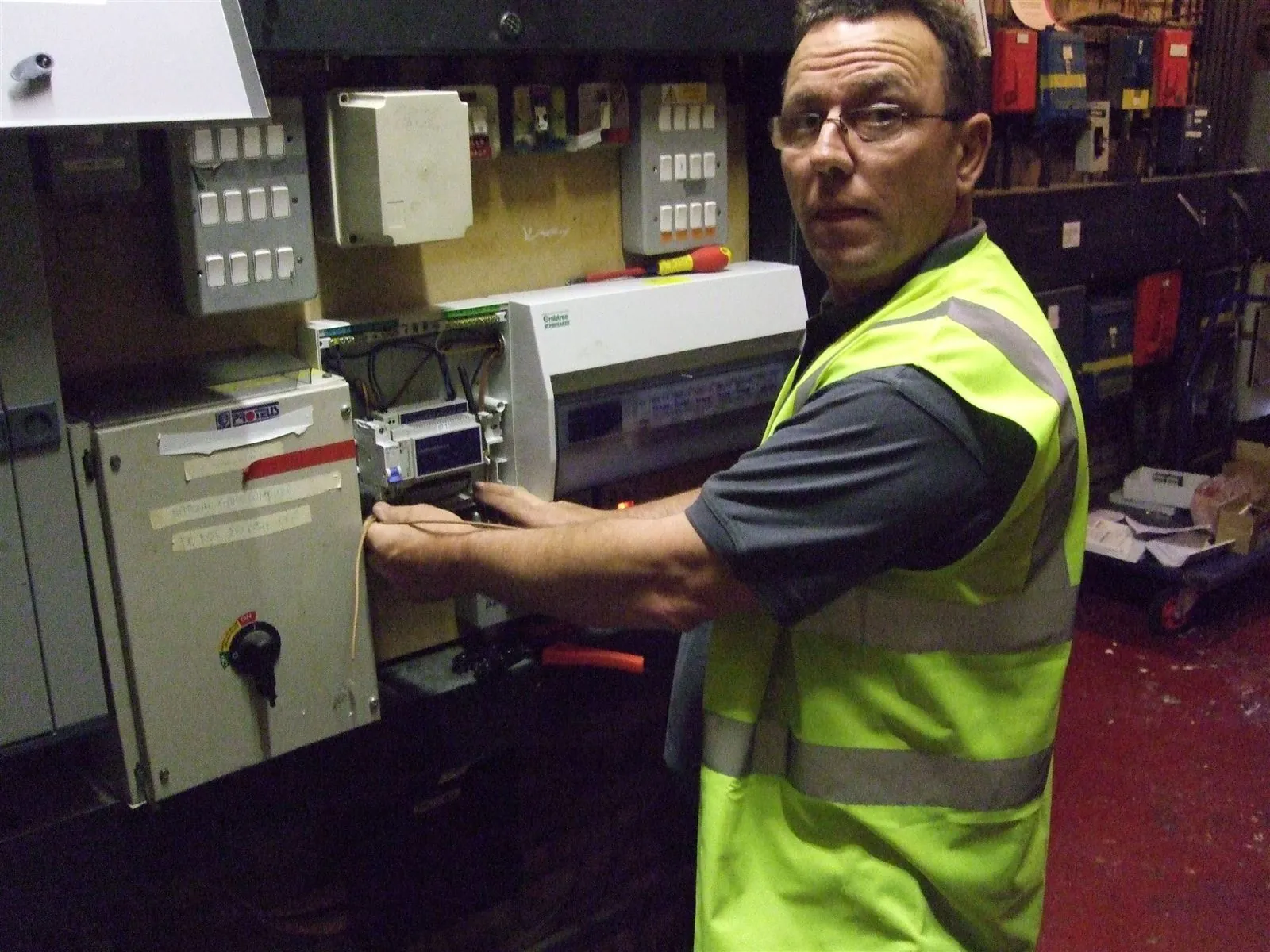 Electrician working at a distribution board in a commercial plant room