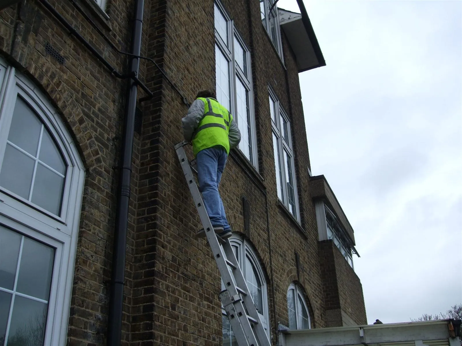 Electrician on a ladder at a brick commercial building