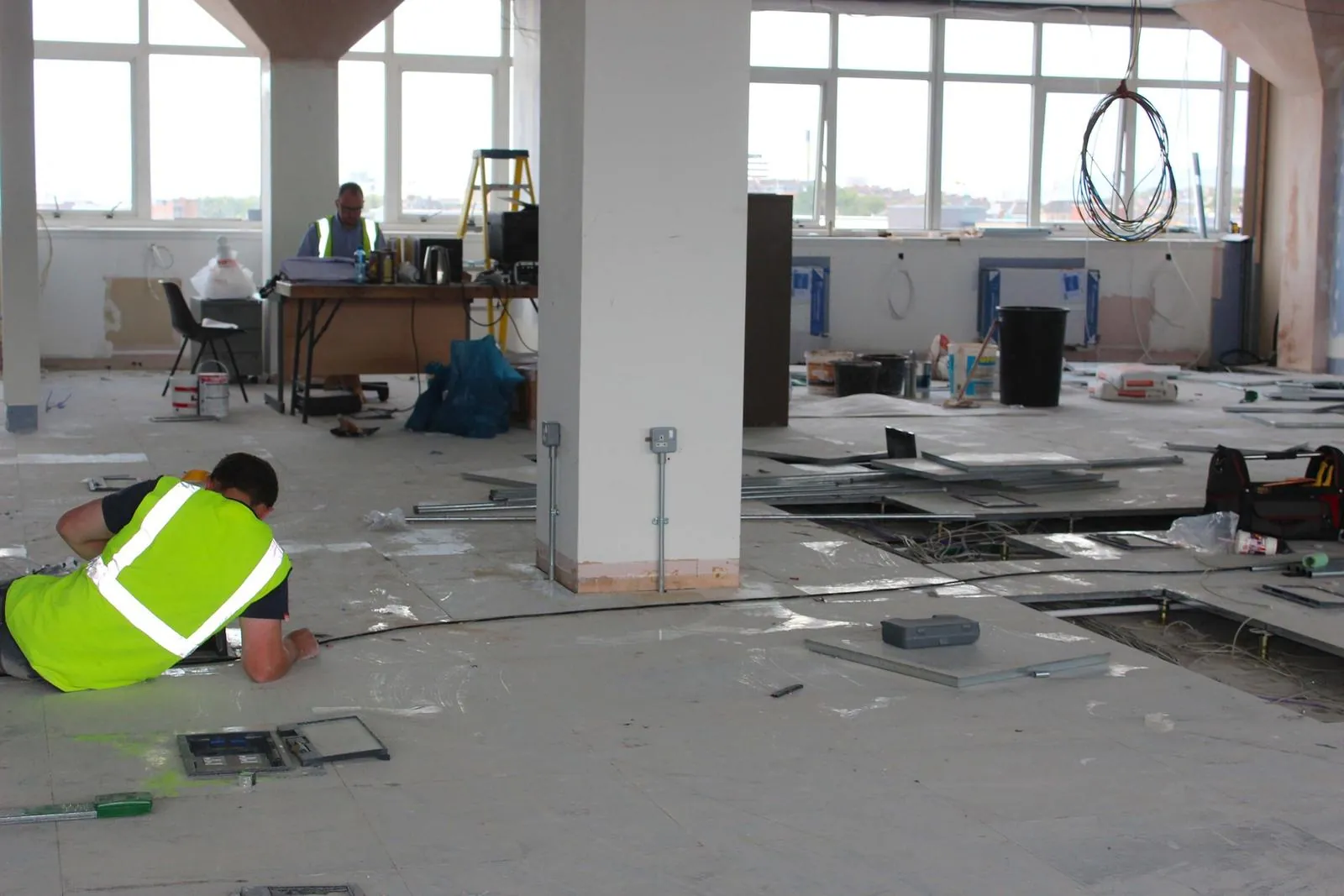 Electrician running cabling under a raised access floor on a commercial fit-out
