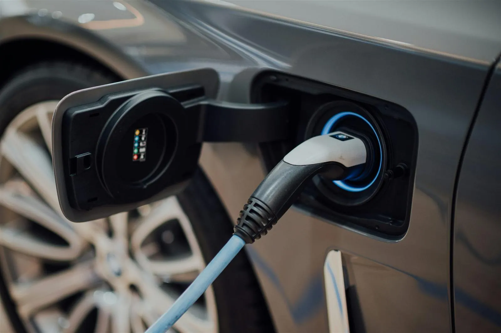 Charging connector plugged into an electric car with the port ring lit blue