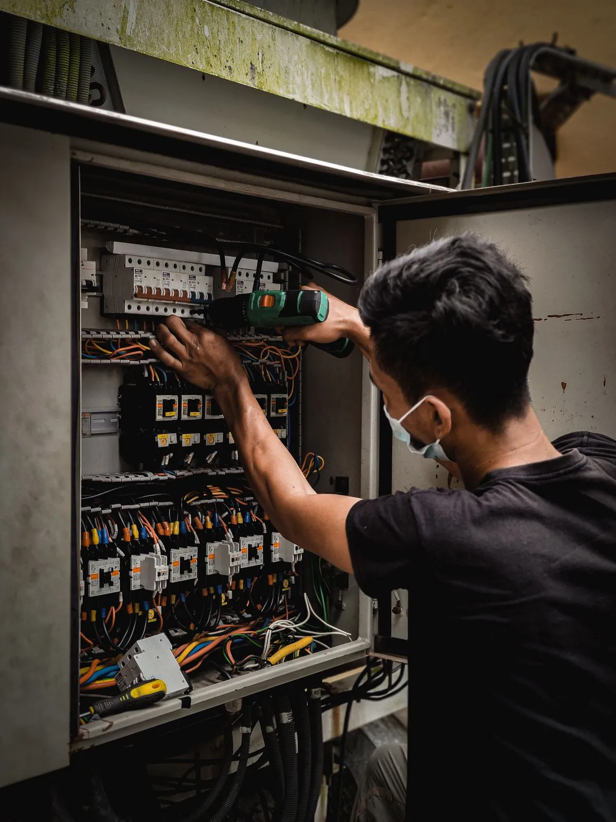 Electrician working inside an industrial control cabinet