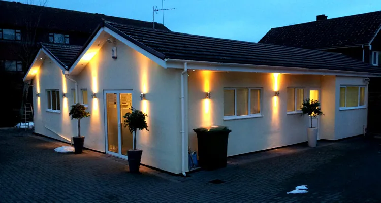 Exterior uplighting installed on a bungalow at dusk