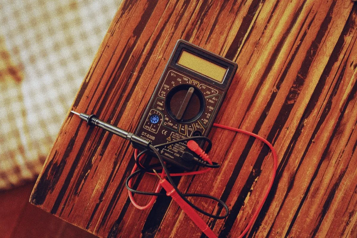 Digital multimeter with red and black test leads on a workbench